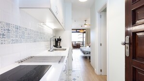 Una cocina moderna con armarios blancos, encimera negra y azulejos de resalte estampados.