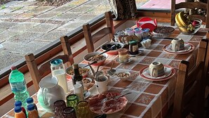 A dining table set with various dishes, drinks, and condiments, surrounded by wooden chairs. - Il Riccio holiday home (Monte Argentario)