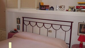 A bedroom with a bed, a bookshelf, and a nightstand. - Il Riccio holiday home (Monte Argentario)