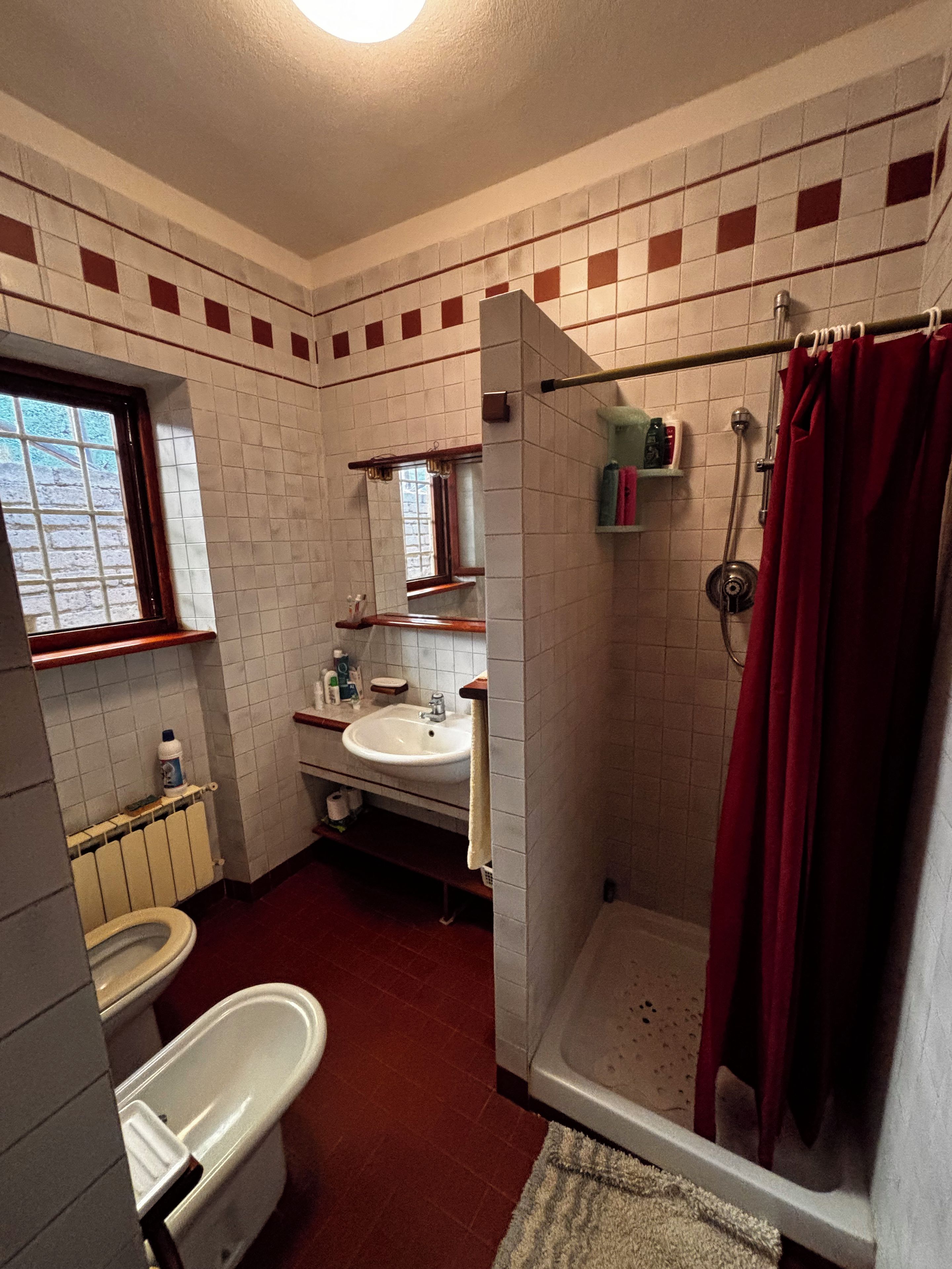 Une salle de bain avec des toilettes, un lavabo, une douche et une fenêtre.