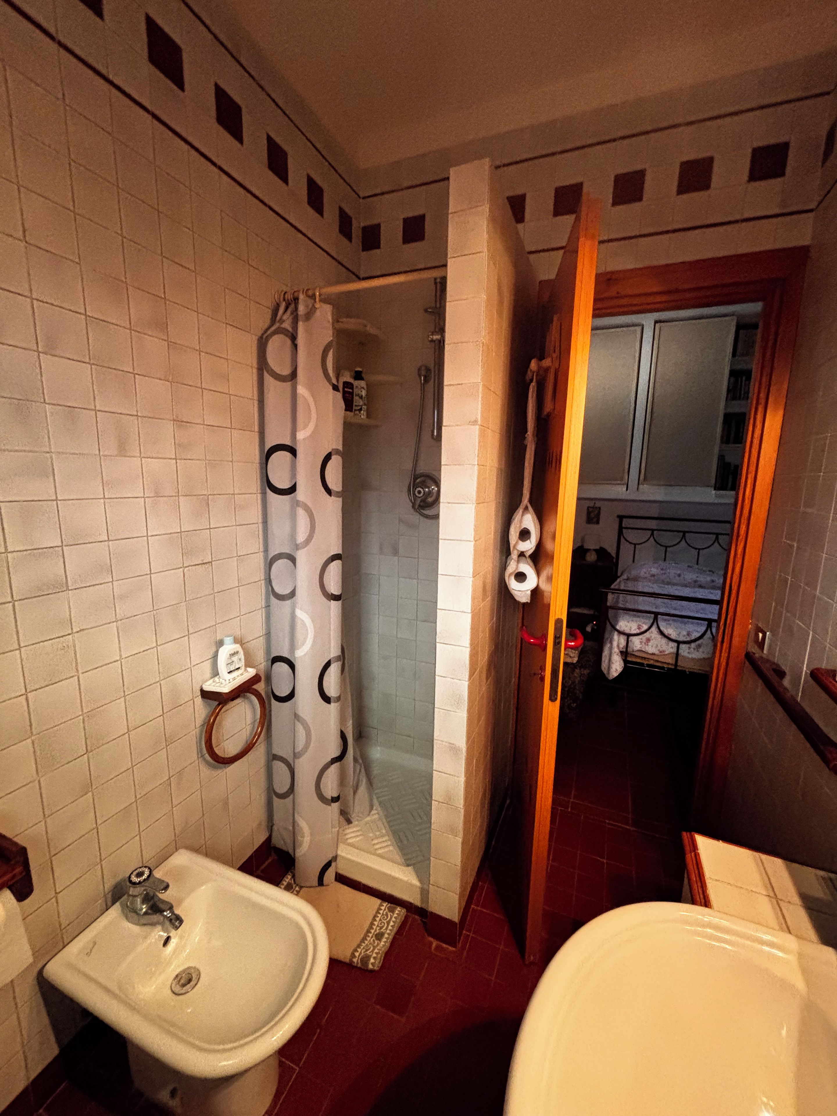 A bathroom with a sink, toilet, shower, and a towel rack.