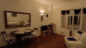 A small living room with a dining table, chairs, a sofa, a TV, and a bookshelf. - FESTIVAL SEA CLASS & CHARME CANNES MONTFLEURY (Cannes)