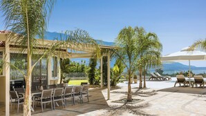 Un'area patio esterna con una pergola, tavoli da pranzo, sedie e poltrone relax.