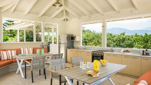 Una cucina moderna con un'ampia finestra, un'area pranzo con tavolo e sedie, e un angolo salotto con divano.