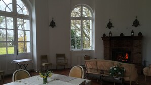 A room with a fireplace, a dining table with a lace tablecloth, and two chairs. - XVII century dovecote (Grémonville)