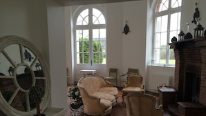 A room with a fireplace, two armchairs, a table, and a large mirror. - XVII century dovecote (Grémonville)