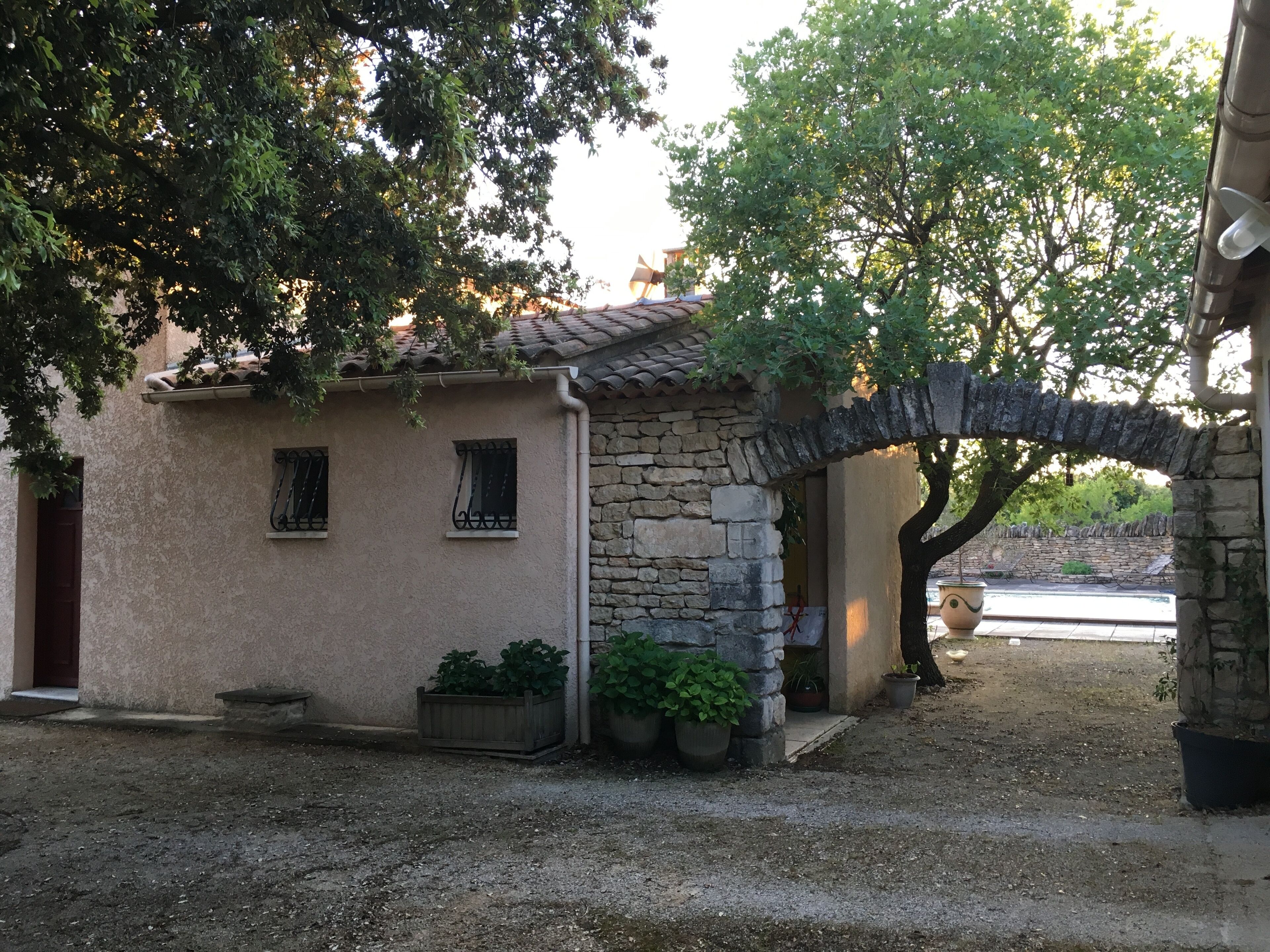 Un bâtiment rustique doté d’une arche en pierre, d’une petite entrée et de plantes en pot.