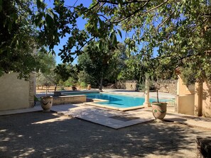 Una piscina rodeada de árboles y muros de piedra.