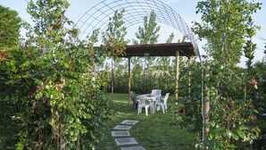 A garden with a pergola, a table with chairs, and a stone pathway. - Agriturismo da Rosi - Marina house with swimming pool (Codevigo)