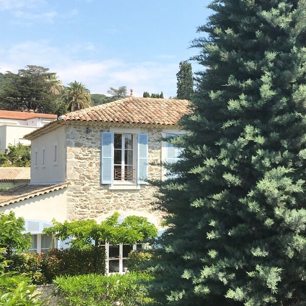 A stone building with a tiled roof and blue shutters, surrounded by greenery. - Bastide du Soleil - Studio 2/4 persons 800 meters from the beach (Cannes)
