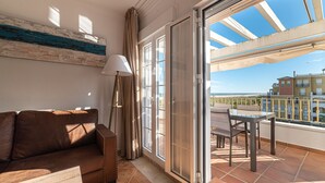 Ein Balkon mit Tisch, Stühlen, einer Couch und einer Lampe.