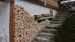 Un escalier en bois mène à une cabane, et une pile de bois de chauffage est appuyée contre le mur.