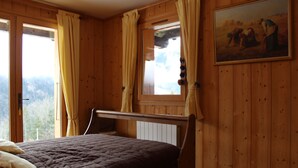 Une pièce en bois avec un lit, une fenêtre avec des rideaux et un tableau accroché au mur.