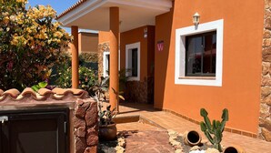 A house with a tiled patio, a covered porch, and a cactus plant. - Casa Piedra - Air Conditioned, Private Pool, Spa,  Pool Table, Frontline Golf (Caleta De Fuste)