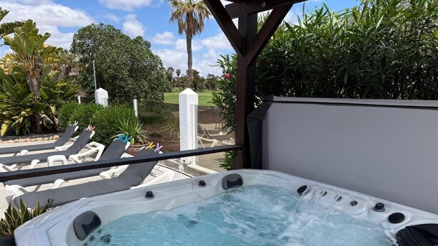 A hot tub with a control panel, surrounded by lounge chairs and greenery. - Casa Piedra - Air Conditioned, Private Pool, Spa,  Pool Table, Frontline Golf (Caleta De Fuste)