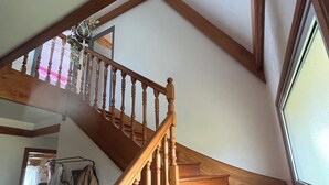 Un escalier en bois, doté d’une rampe, menant à un palier avec une fenêtre.