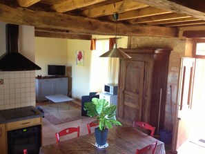 Une cuisine rustique avec un plafond en bois, un mur recouvert de carreaux, une cuisinière et une table à manger avec des chaises.