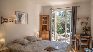 A bedroom with a bed, a wooden cabinet, a desk, and a chair. - Charming studio in villa in Saint Paul de Vence with terrace and garden (Saint-Paul-De-Vence)