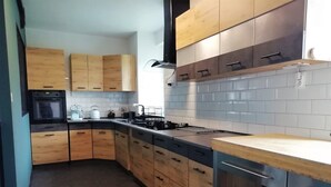 Een moderne keuken met houten kastjes, een roestvrijstalen fornuis en een betegelde achterwand.