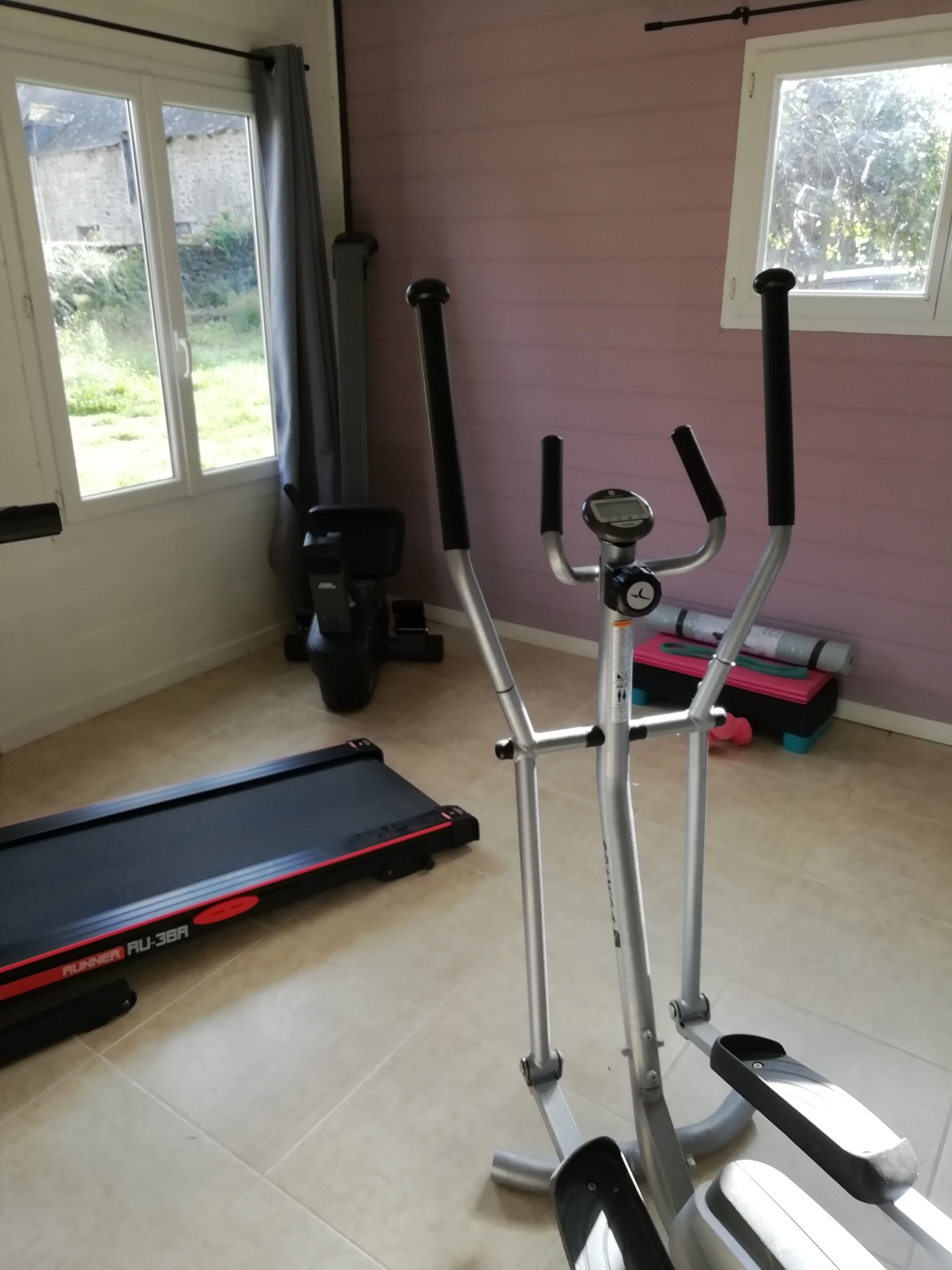 A home gym with a treadmill, elliptical, and weights.