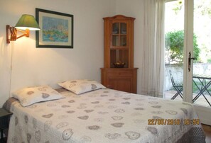 Ein Schlafzimmer mit einem Bett, Kissen, einer Lampe, einem Schrank und einem Fenster.