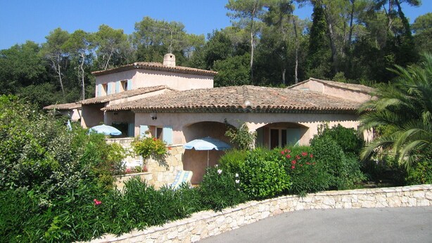 Eine Villa im mediterranen Stil mit Ziegeldach, Steinmauern und einem steinbelagten Weg zum Eingang.