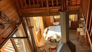 Interior d'una cabana amb un lliter doble, una llar de foc, zona de menjador i televisió.