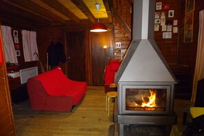 Une pièce chaleureuse avec un poêle à bois, des murs en bois et un canapé rouge.