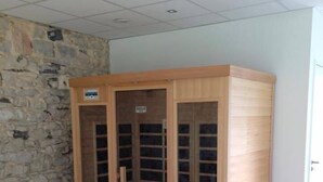 Un meuble en bois doté de portes en verre, situé dans une pièce dont le mur est en pierre et le sol en bois.