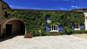 A building with a stone facade, blue shutters, and a gravel courtyard. - Family 2-bedroom gîte - Cognac countryside, pool, games room, pet friendly (Segonzac)