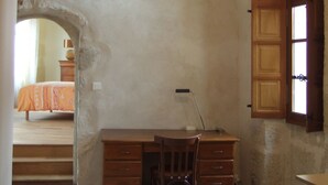 Une pièce comprenant un bureau, une chaise et une porte en bois ouverte donnant sur une autre pièce.