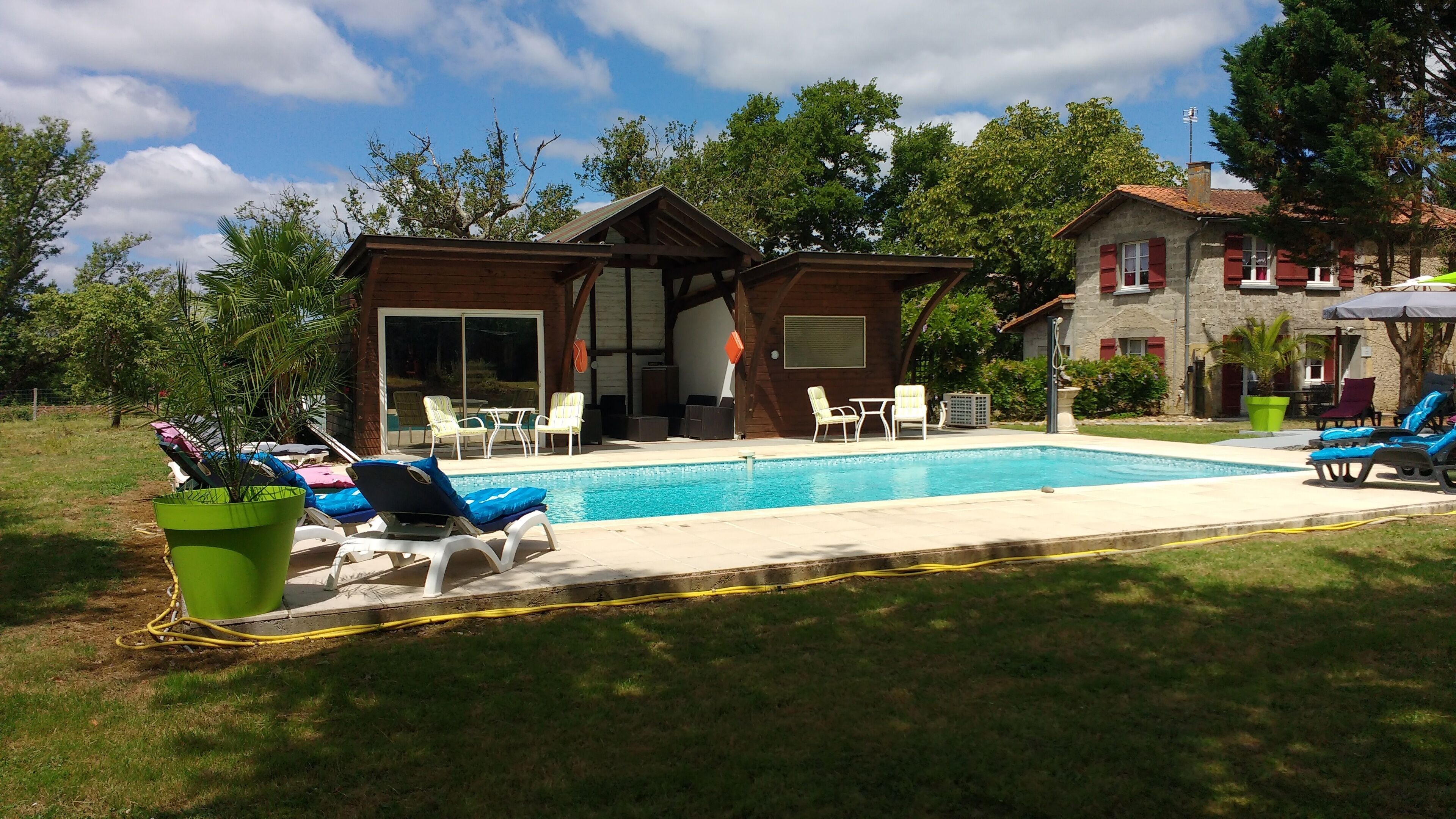 A poolside area with lounge chairs, a small table, and a covered seating area.