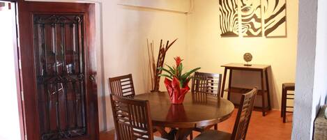A dining area with a wooden table and chairs, a decorative vase, and a wall with abstract art.
