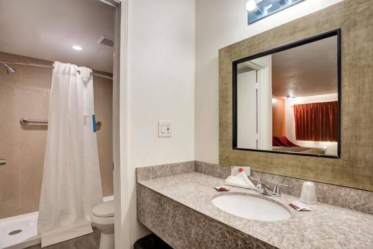 A bathroom with a shower, toilet, sink, and mirror.
