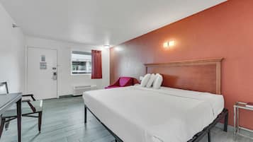 A hotel room with a bed, a desk, and a chair.