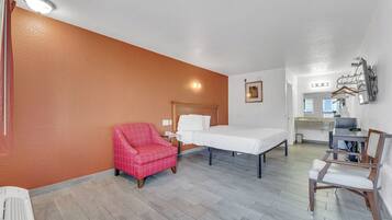 Habitación de hotel con cama, una silla, un escritorio y kitchenette.