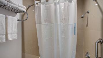 A bathroom with a shower curtain, a towel rack with towels, a toilet, and a handrail.