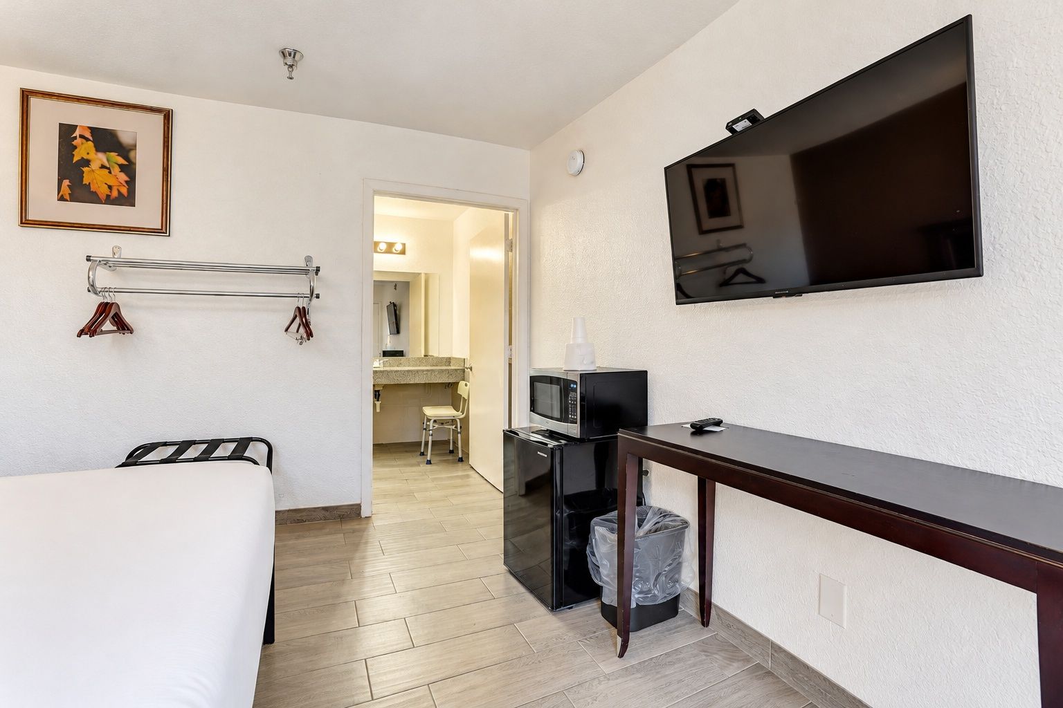 Habitació d'hotel amb un llit, escriptori, televisió, microones i paperera.