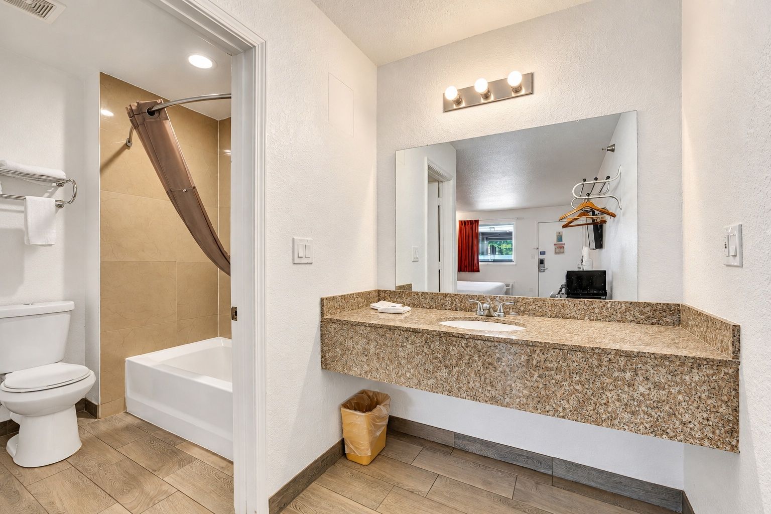 A bathroom with a bathtub, toilet, sink, and vanity mirror.