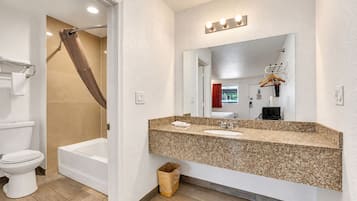 A bathroom with a bathtub, toilet, sink, and vanity mirror.