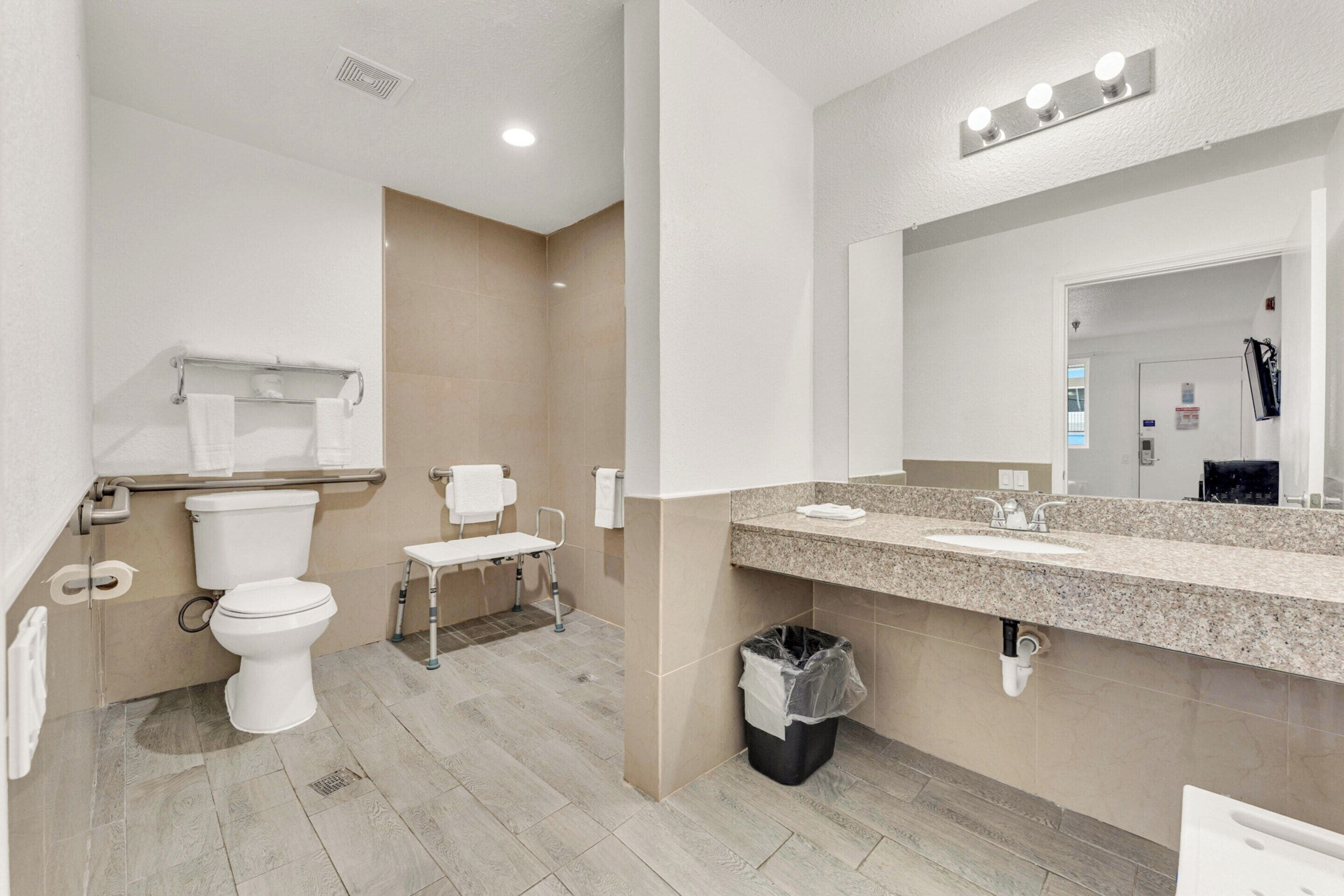 Un baño moderno con inodoro, lavamanos y espejo.