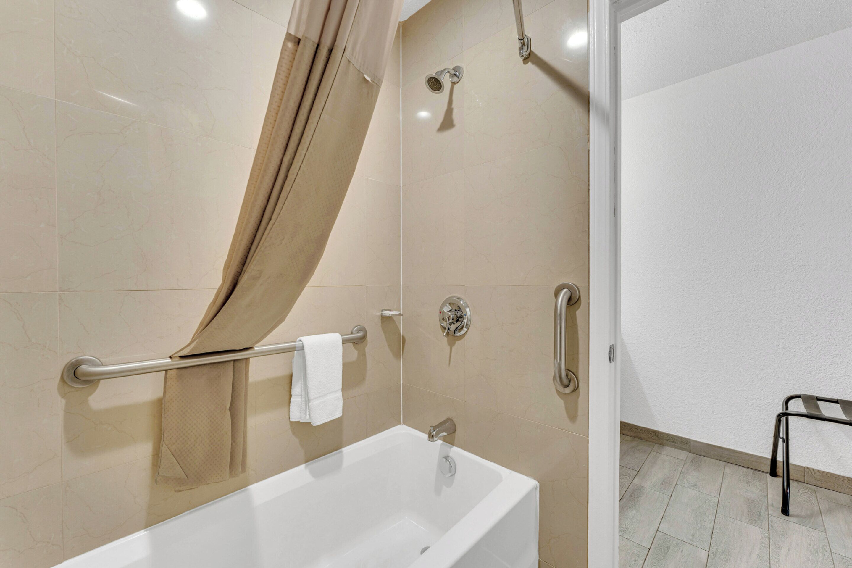 Un baño moderno con bañera, ducha y barras de apoyo.