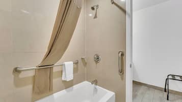 A modern bathroom with a bathtub, shower, and grab bars.
