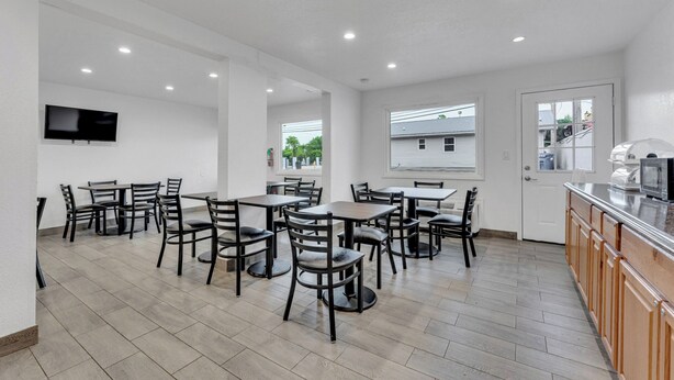 A spacious dining area with multiple tables and chairs, a kitchen area with a microwave, and a television mounted on the wall. - Motel 6 Branson, MO (Branson)