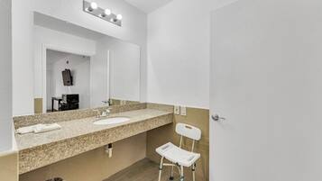A bathroom with two sinks, a mirror, a vanity, and a white chair.