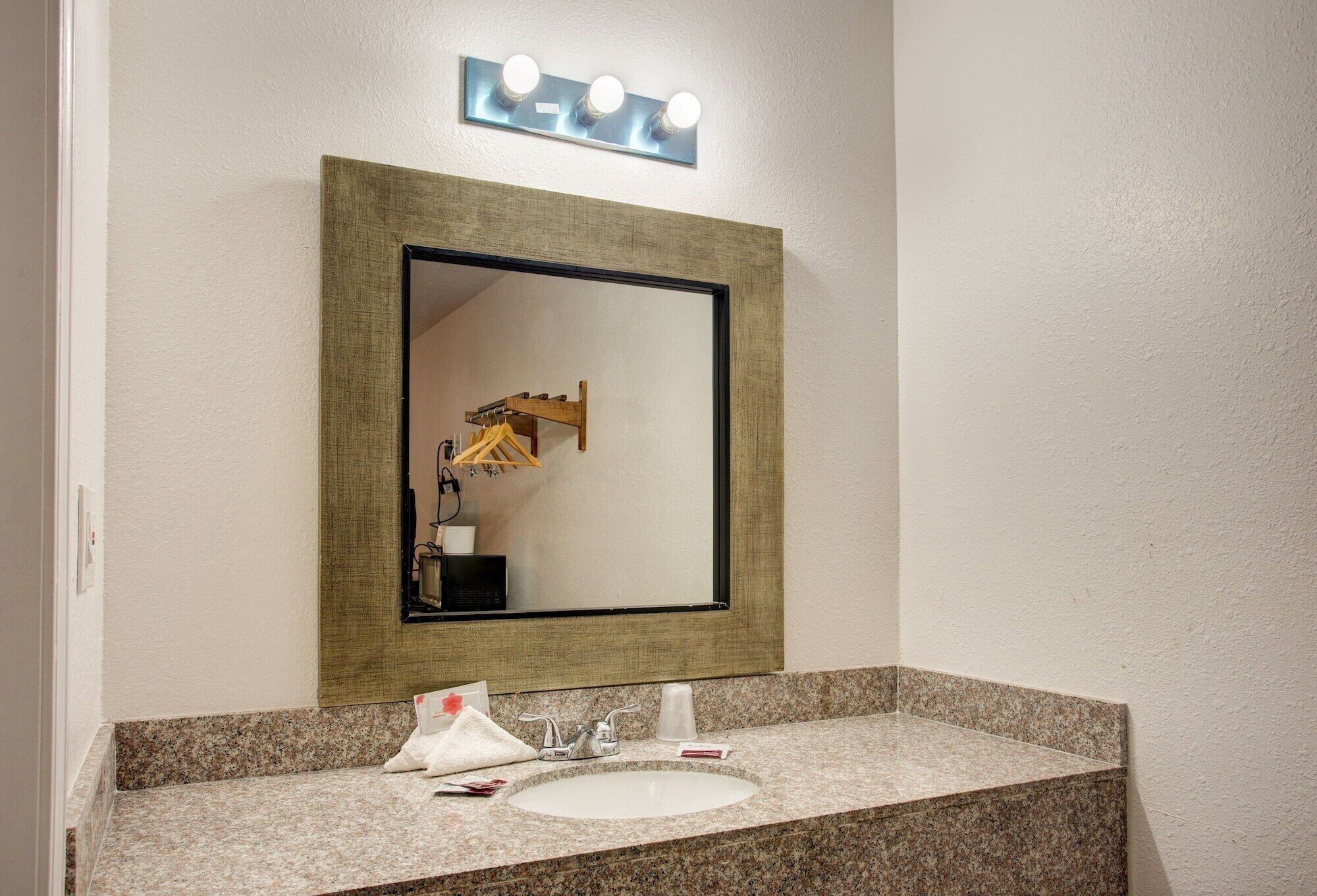Une salle de bain avec un grand miroir, un lavabo et un meuble-lavabo.