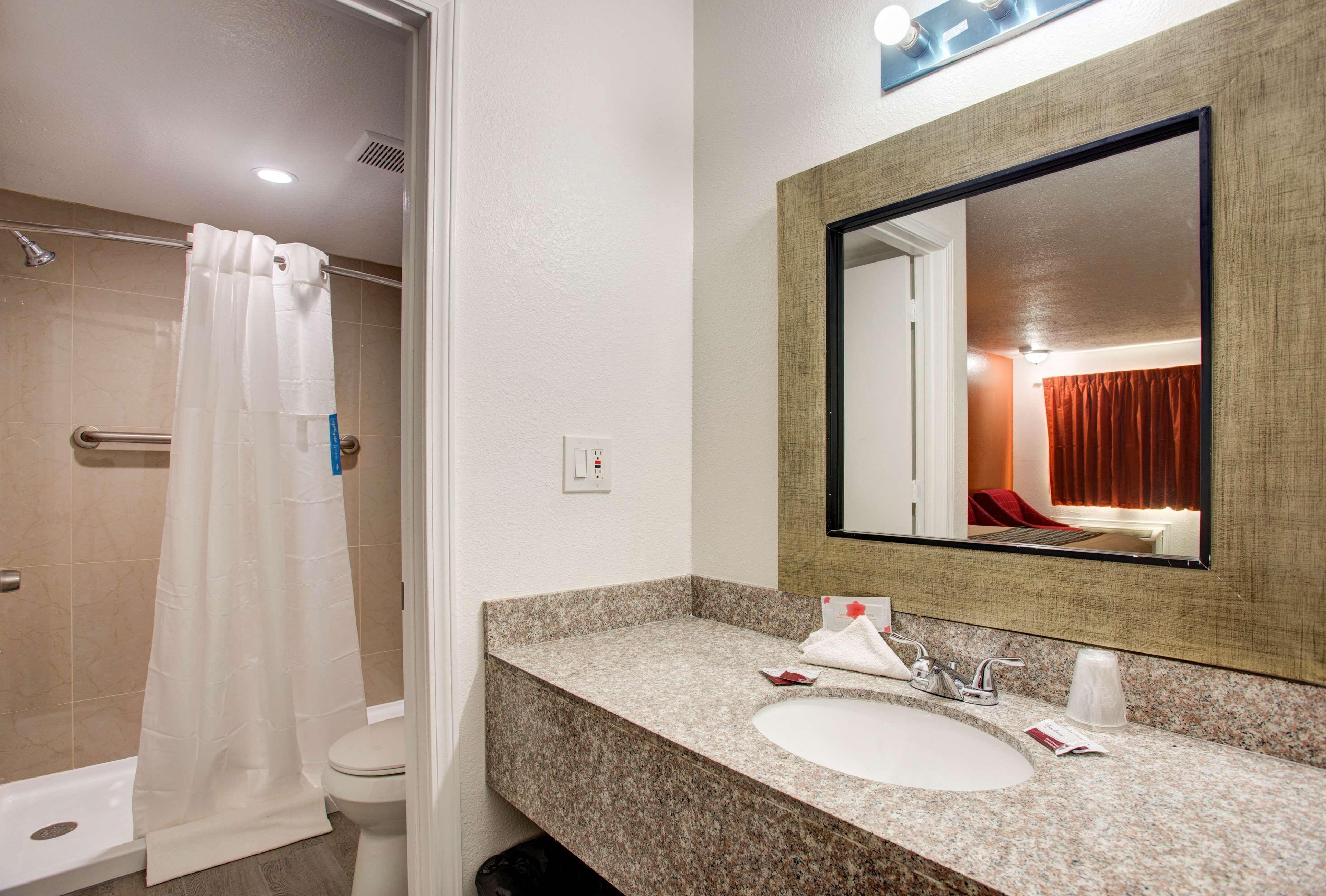 A bathroom with a shower, toilet, sink, and mirror.