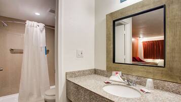 A bathroom with a shower, toilet, sink, and mirror.