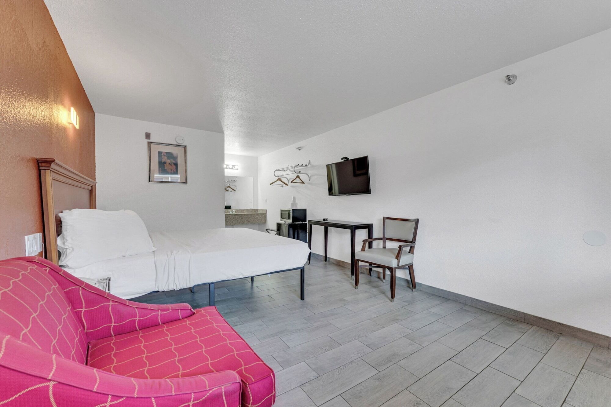Een hotelkamer met een bed, een bureau, een stoel, een televisie en een klein tafeltje.