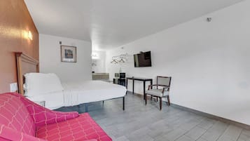 Une chambre d’hôtel équipée d’un lit, d’un bureau, d’une chaise, d’une télévision et d’une petite table.